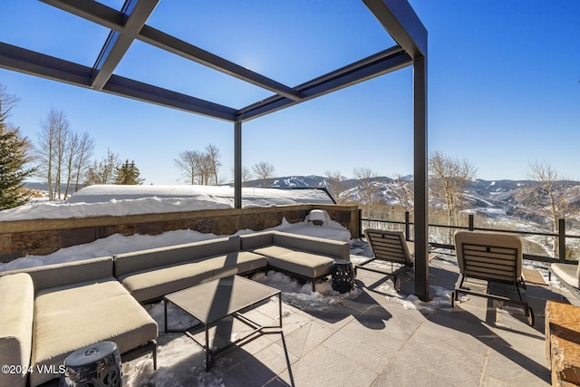 snow covered patio featuring a mountain view, a lanai, and outdoor lounge area