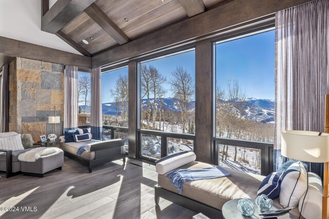 interior space with a mountain view, wood ceiling, and lofted ceiling with beams