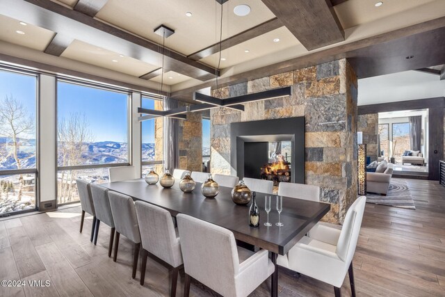 dining room with a multi sided fireplace, beam ceiling, and wood finished floors