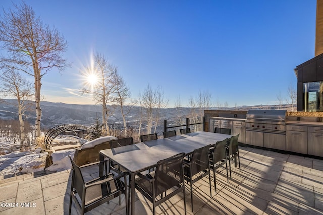 view of patio with outdoor dining area, area for grilling, an outdoor kitchen, and a mountain view