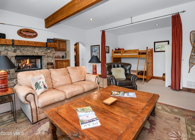 2241 Tahoe Dr, Vail, CO 81657 - living room with arched walkways, beam ceiling, a stone fireplace, and light carpet