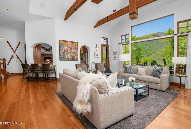 2241 Tahoe Dr, Vail, CO 81657 - living area with arched walkways, beamed ceiling, light wood-style floors, a glass covered fireplace, and high vaulted ceiling
