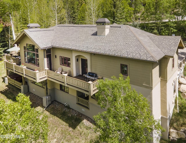 2241 Tahoe Dr, Vail, CO 81657 - rear view of house with a shingled roof, a deck, a chimney, and a view of trees