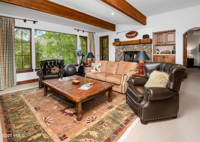 2241 Tahoe Dr, Vail, CO 81657 - living room with arched walkways, a stone fireplace, beamed ceiling, and baseboards