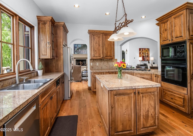 2241 Tahoe Dr, Vail, CO 81657 - kitchen with black appliances, a sink, arched walkways, a kitchen island, and light wood-type flooring