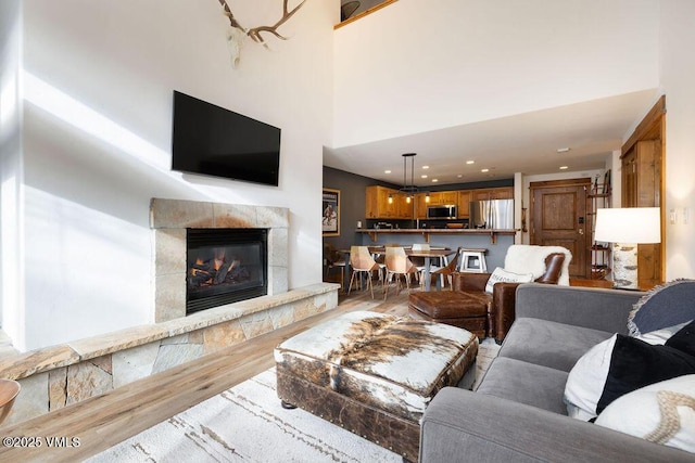 living room with recessed lighting, a fireplace, a high ceiling, and wood finished floors