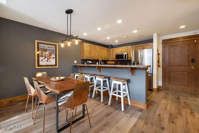 dining area featuring recessed lighting, baseboards, and light wood finished floors