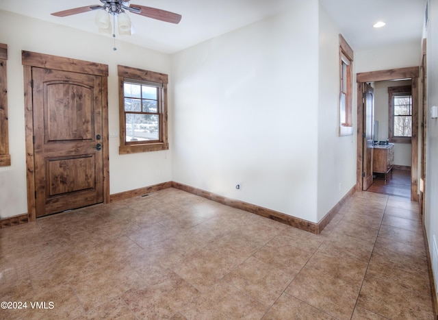 spare room with a ceiling fan, a wealth of natural light, and baseboards