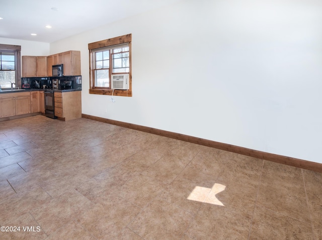 kitchen with a sink, baseboards, decorative backsplash, black appliances, and dark countertops