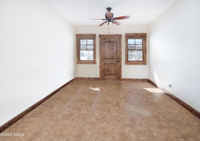 spare room featuring a ceiling fan, a healthy amount of sunlight, and baseboards