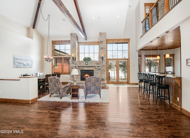 living area with a warm lit fireplace, high vaulted ceiling, a notable chandelier, and wood finished floors