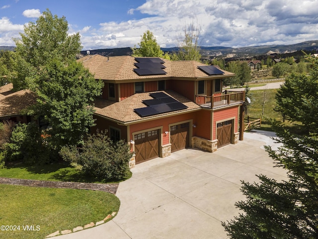 view of front of property featuring solar panels, stone siding, concrete driveway, and a front yard