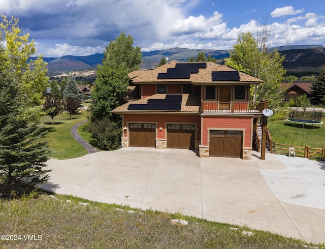 view of front facade featuring stone siding, a trampoline, a mountain view, and a front yard