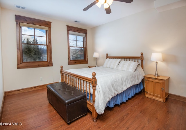 bedroom with ceiling fan, wood finished floors, visible vents, and baseboards