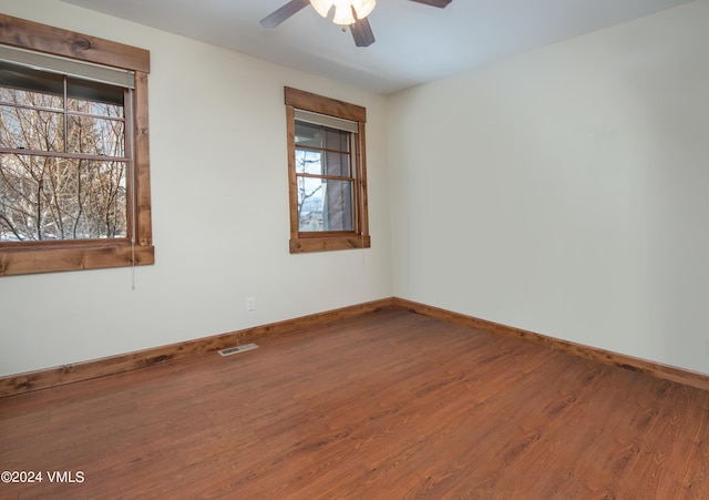 empty room with a ceiling fan, visible vents, baseboards, and wood finished floors