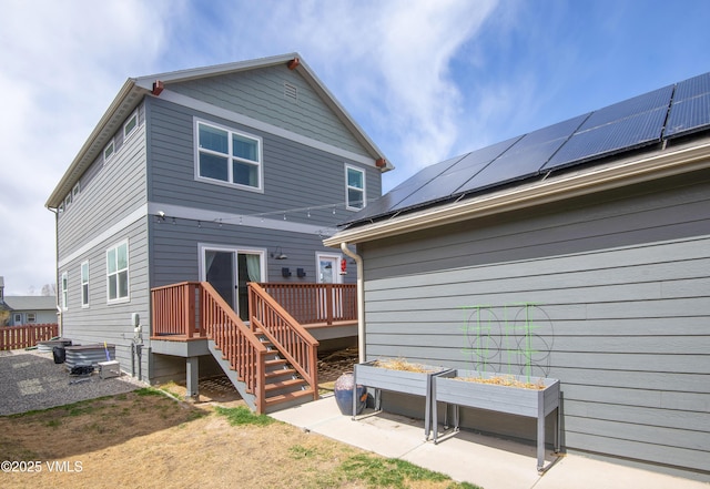 back of house featuring solar panels and a wooden deck