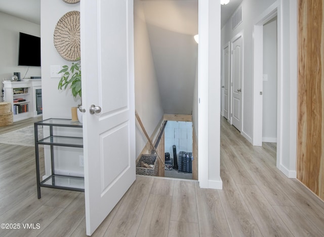 hallway featuring visible vents, baseboards, and wood finished floors