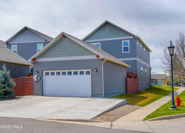 craftsman-style house with a garage, concrete driveway, a front yard, and fence