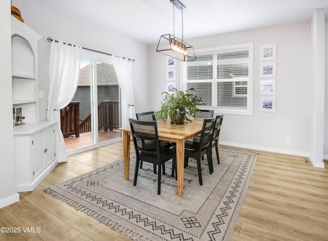 dining area with light wood-style flooring, built in features, and baseboards