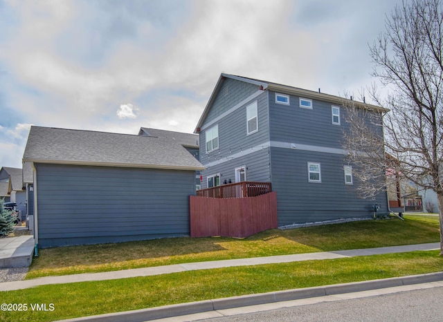 view of side of home featuring a lawn and fence