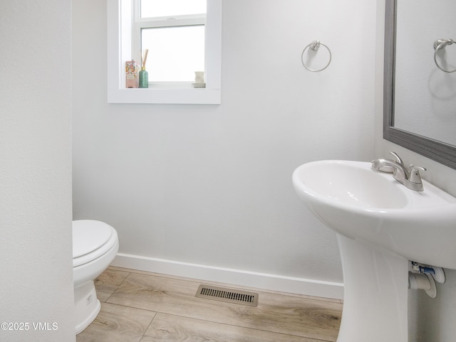 half bath with visible vents, toilet, and baseboards