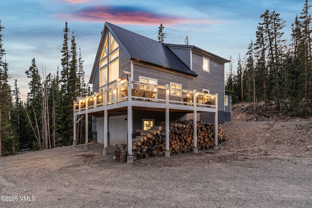 408 El Lobo Ln, Fairplay, CO 80440 - back of house at dusk featuring an attached garage, a wooden deck, dirt driveway, and a metal roof