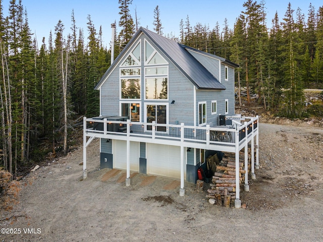 408 El Lobo Ln, Fairplay, CO 80440 - back of property with dirt driveway, an attached garage, a wooden deck, a view of trees, and a metal roof