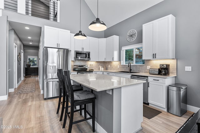 408 El Lobo Ln, Fairplay, CO 80440 - kitchen with appliances with stainless steel finishes, a kitchen island, light wood finished floors, white cabinetry, and a towering ceiling