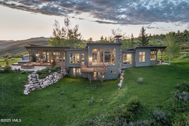 6306 Bellyache Ridge Rd, Wolcott, CO 81655 - back of house at dusk with a patio, a yard, a mountain view, and a sunroom