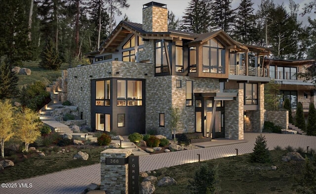 366 Forest Rd, Vail, CO 81657 - view of front of house featuring stone siding, a balcony, a chimney, and a standing seam roof