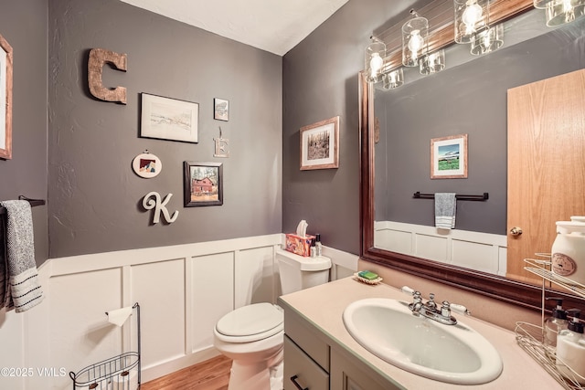1000 Homestead Dr Unit 30, Edwards, CO 81632 - half bathroom with a wainscoted wall, a decorative wall, vanity, toilet, and wood finished floors
