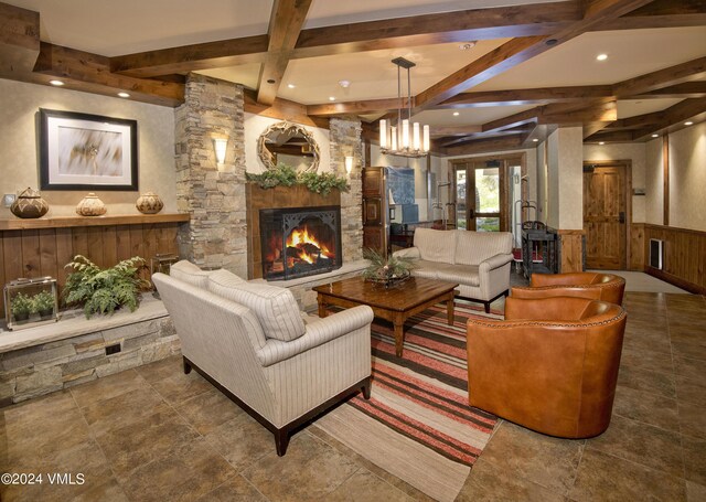 living room featuring beamed ceiling and a stone fireplace