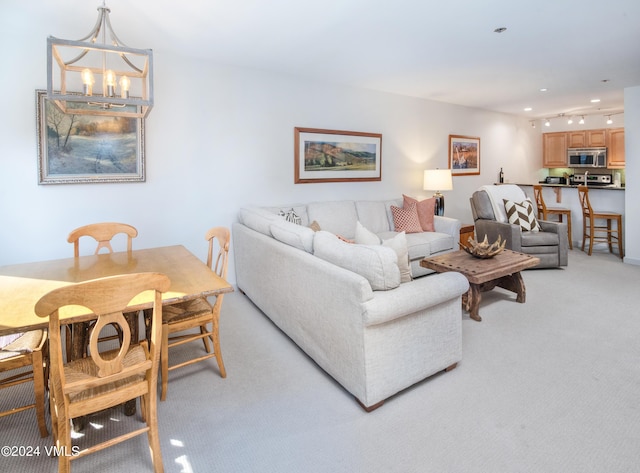 carpeted living room with an inviting chandelier