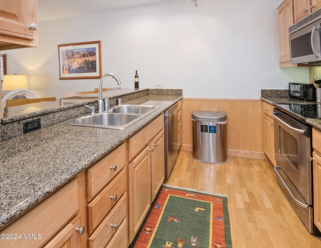 kitchen with sink, light hardwood / wood-style flooring, stainless steel appliances, and light stone countertops