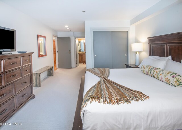 carpeted bedroom featuring connected bathroom and a closet