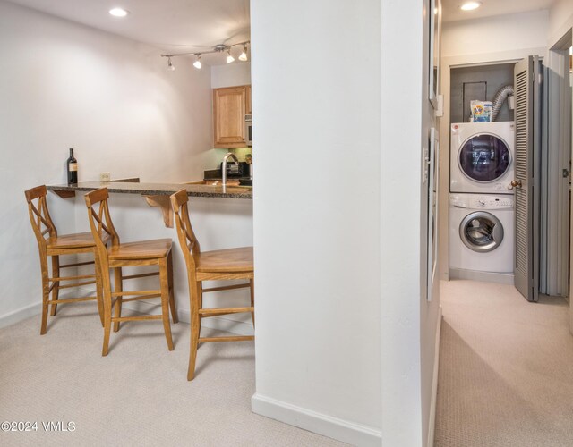 carpeted dining room featuring stacked washer / drying machine and sink