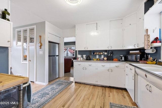 618 W Chestnut St, Leadville, CO 80461 - kitchen with freestanding refrigerator, light countertops, black microwave, light wood-style floors, and white cabinetry