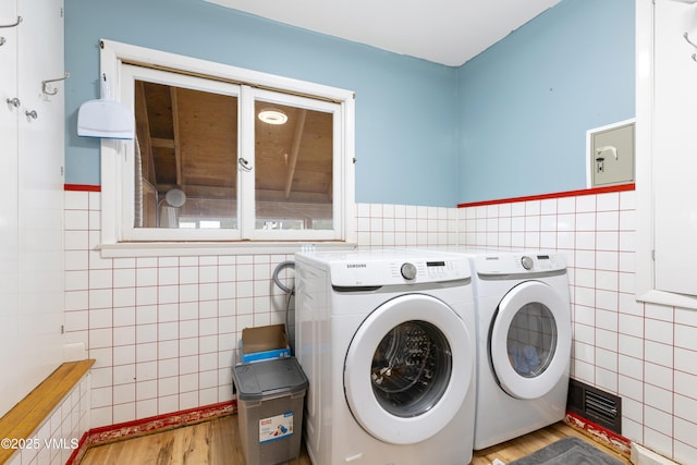 618 W Chestnut St, Leadville, CO 80461 - clothes washing area with tile walls, washer and clothes dryer, wood finished floors, and wainscoting
