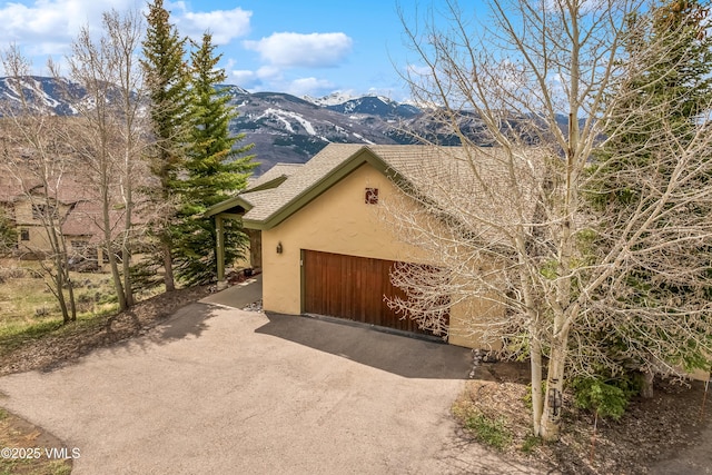 view of front of home featuring a mountain view, stucco siding, an attached garage, and driveway