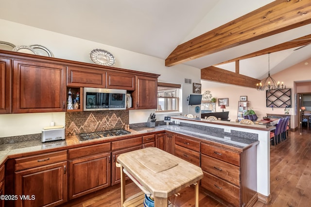 kitchen featuring tile countertops, lofted ceiling with beams, a peninsula, an inviting chandelier, and stainless steel appliances