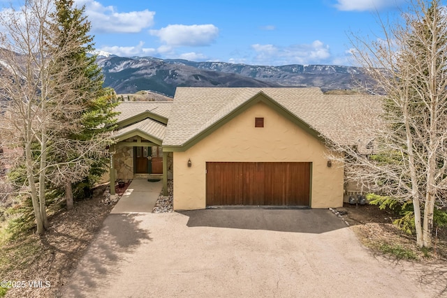 view of front of house with an attached garage, a mountain view, stucco siding, and driveway