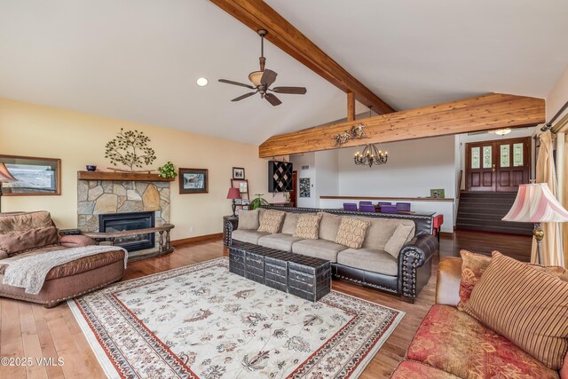 living area featuring a fireplace, beam ceiling, ceiling fan with notable chandelier, and wood finished floors