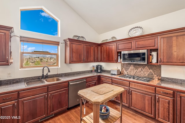 kitchen featuring dark countertops, a sink, light wood finished floors, stainless steel appliances, and visible vents
