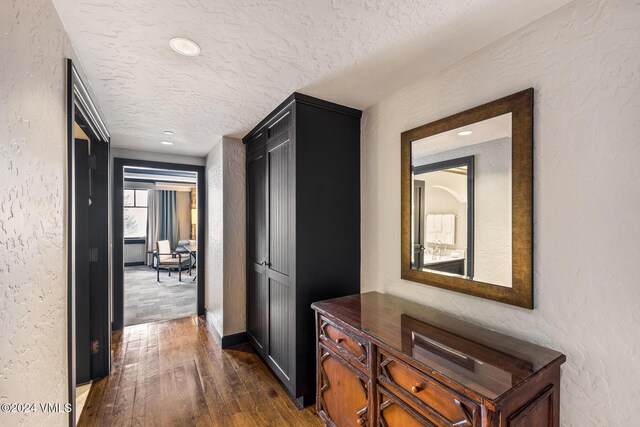 hallway featuring dark hardwood / wood-style flooring and a textured ceiling