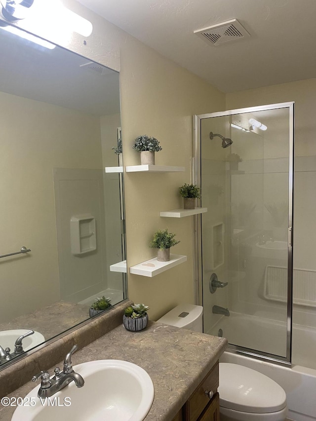 full bathroom featuring vanity, bath / shower combo with glass door, and toilet