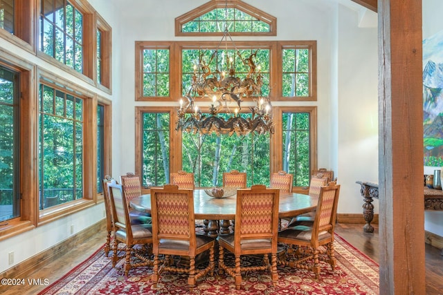 dining space with a high ceiling, hardwood / wood-style flooring, and a chandelier