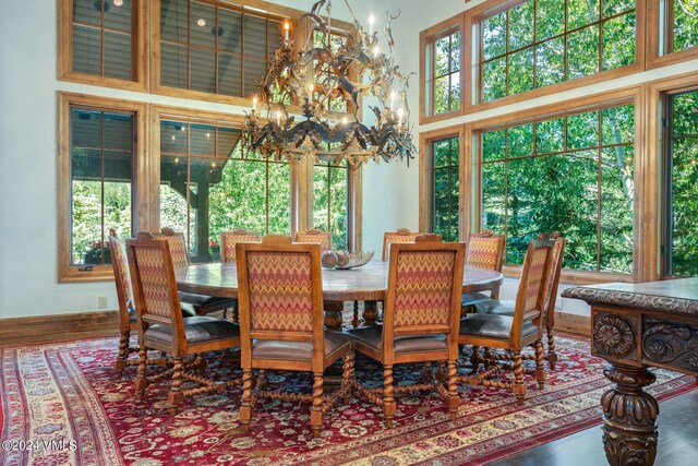 dining room featuring a high ceiling, hardwood / wood-style flooring, a healthy amount of sunlight, and a notable chandelier