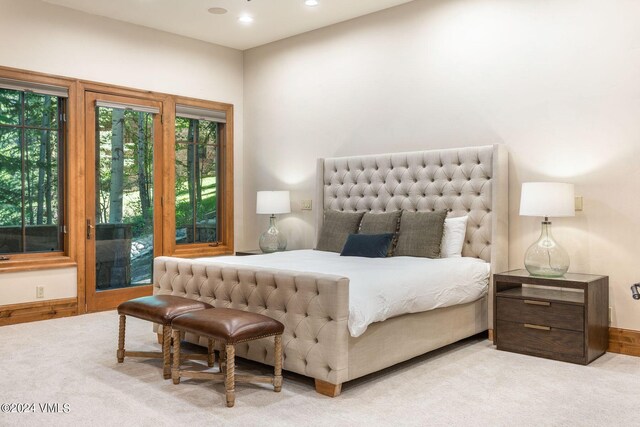 living room featuring beam ceiling, a stone fireplace, light colored carpet, and french doors