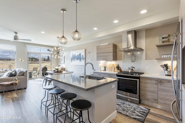 kitchen with wall chimney range hood, modern cabinets, appliances with stainless steel finishes, and a sink