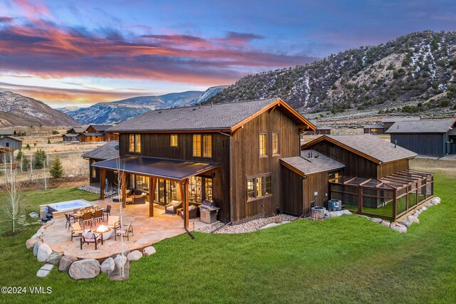 367 Hunters View Ln, Eagle, CO 81631 - back of property at dusk featuring a mountain view, a patio, a lawn, roof with shingles, and an outdoor fire pit
